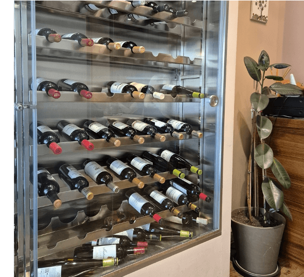Vinoteca climatizada en Saraiba Restaurante con botellas de vinos gallegos y una planta decorativa, reflejando el ambiente acogedor para maridajes en Madrid